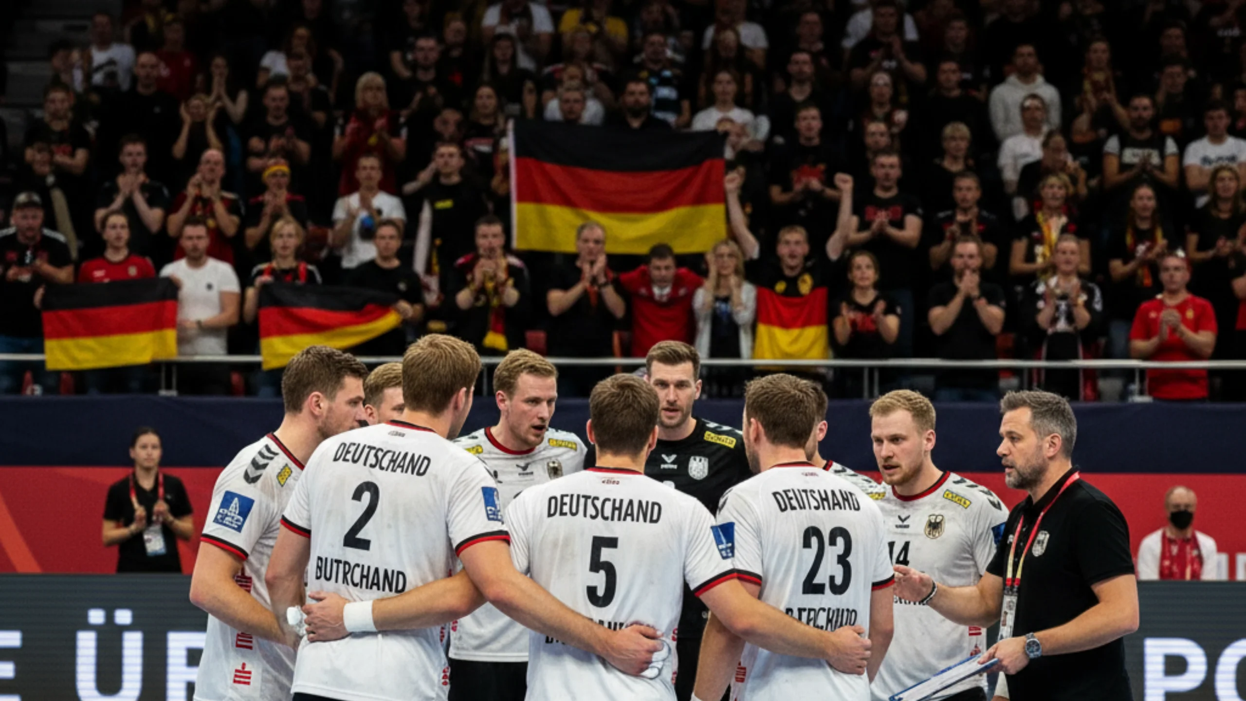 Deutsche Handball-Nationalmannschaft im Teamkreis während eines WM-Spiels mit motivierender Geste